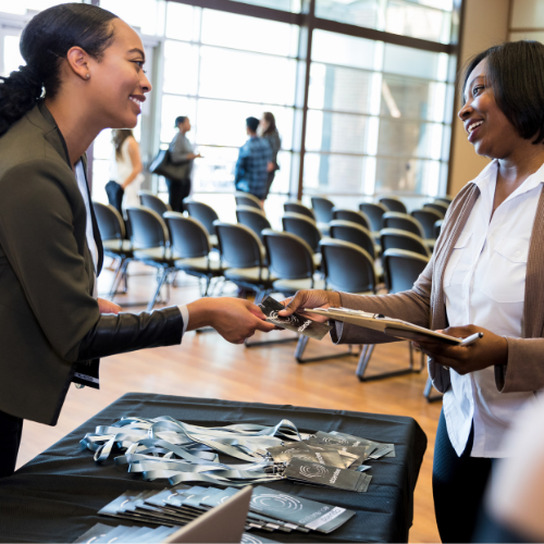  Lady handing attendee lanyard and attachment
